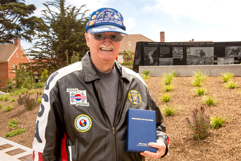 Veteran holding medal in front of Korean War Memorial