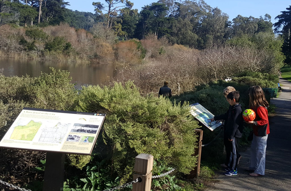 Three kids pointing and reading wayside at Mountain Lake