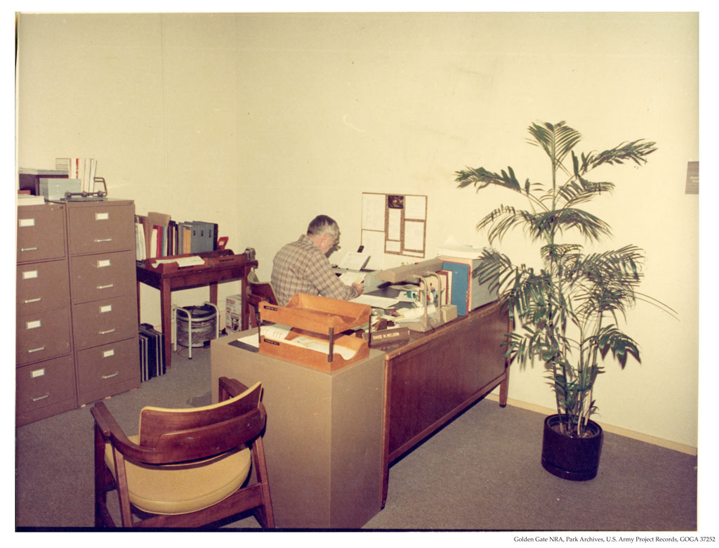 Man back turned looking over paper on typewriter at office desk