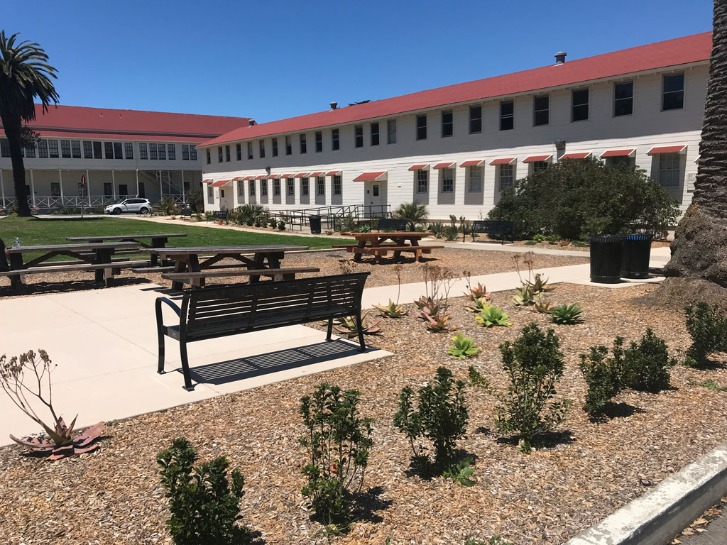 Bench and picnic tables at Civil War Parade Ground by lawn and white buildings