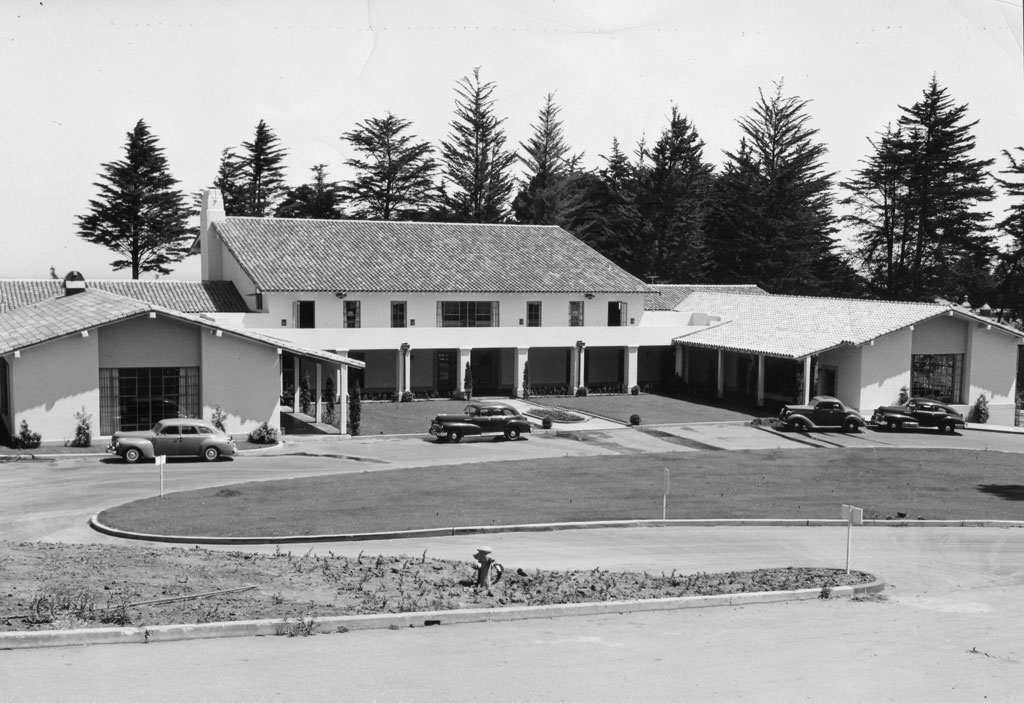 The Enlisted Service Club building with cars parked in front