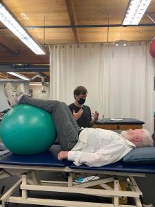 A trainer assists a client who is lying on a table at Presidio Sport & Medicine. Photo by Musa Manneh.