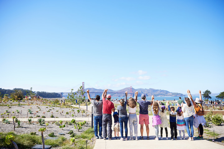 Group of people at Presidio Tunnel Tops facing away from camera to look at Golden Gate Bridge.