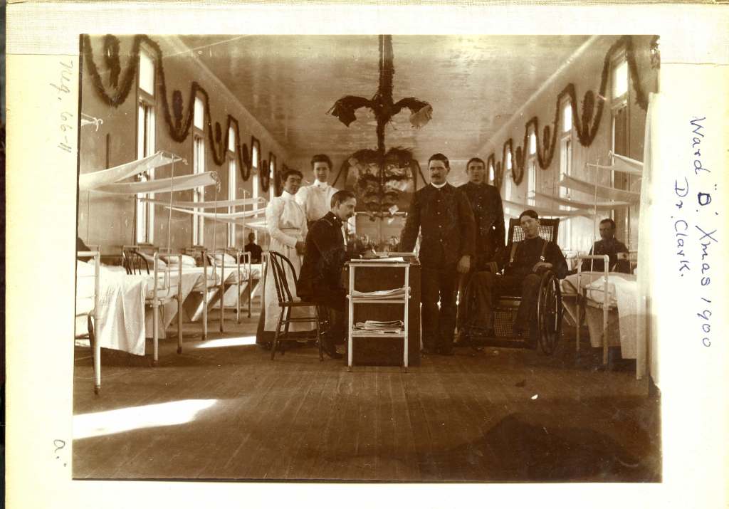 Black and white photo of military personal, patients, and nurses at Letterman General Hospital, Ward D, December 1900.