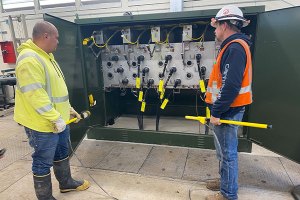 A couple employees in front of substation panel