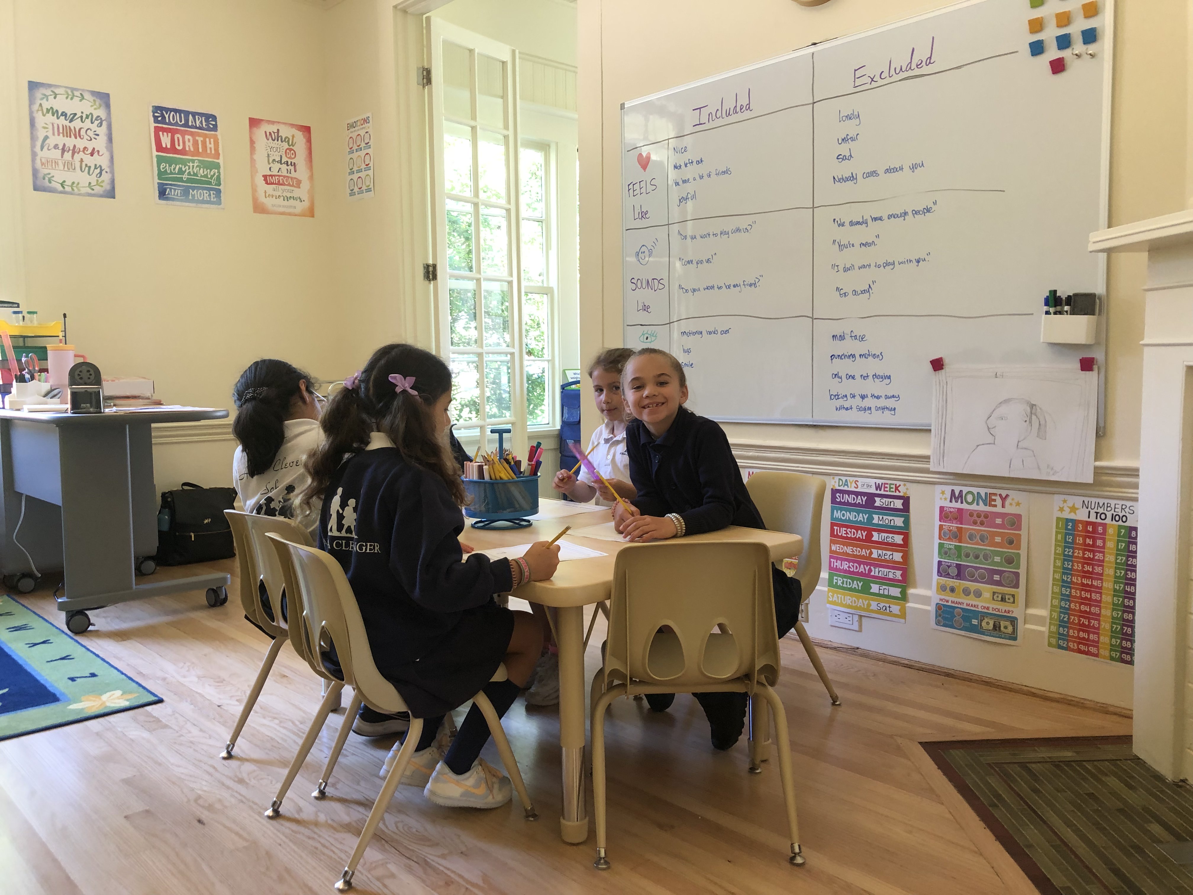 Smiling student at table with other kids